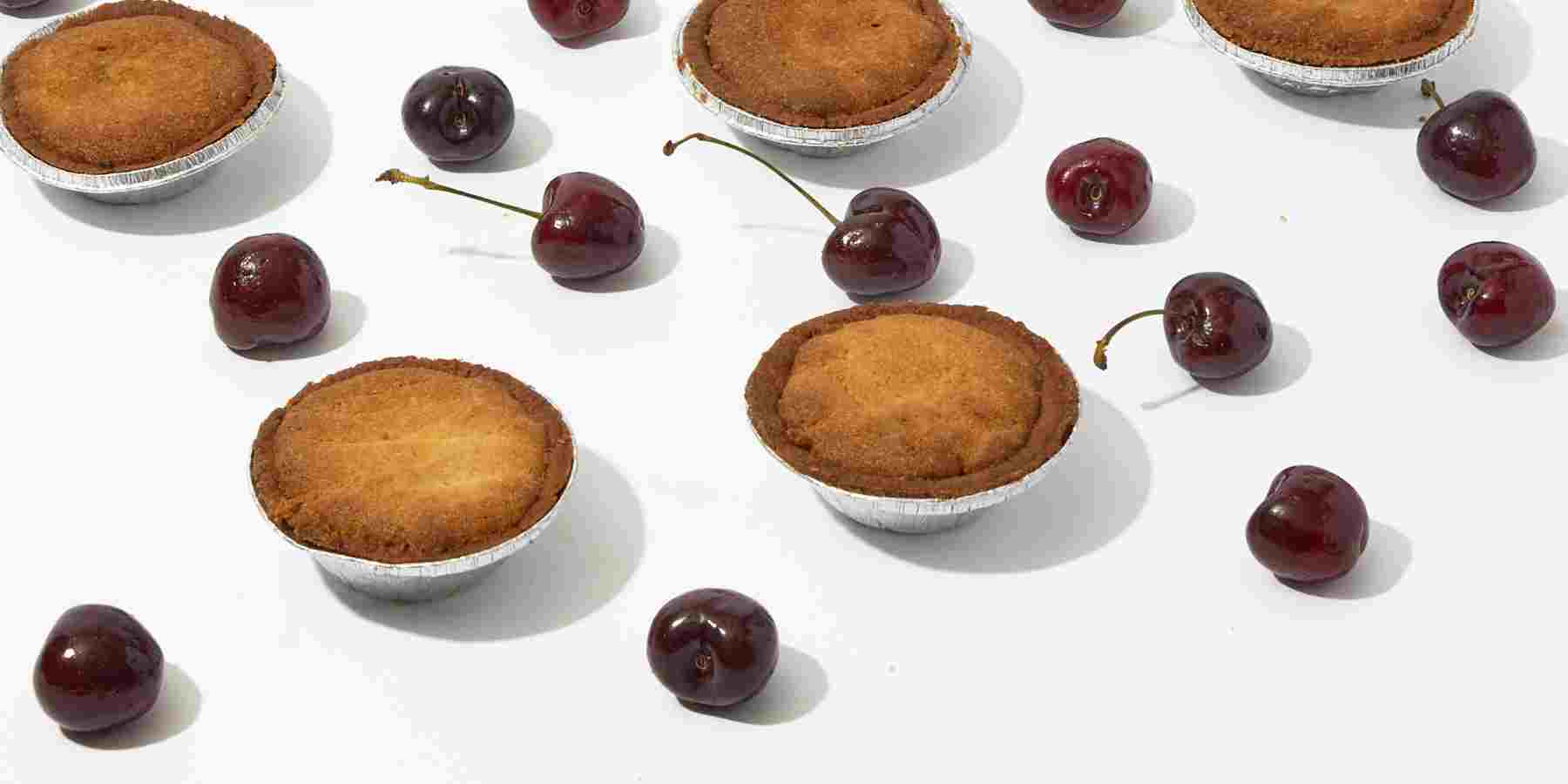 A group of cherry pies on a white surface.