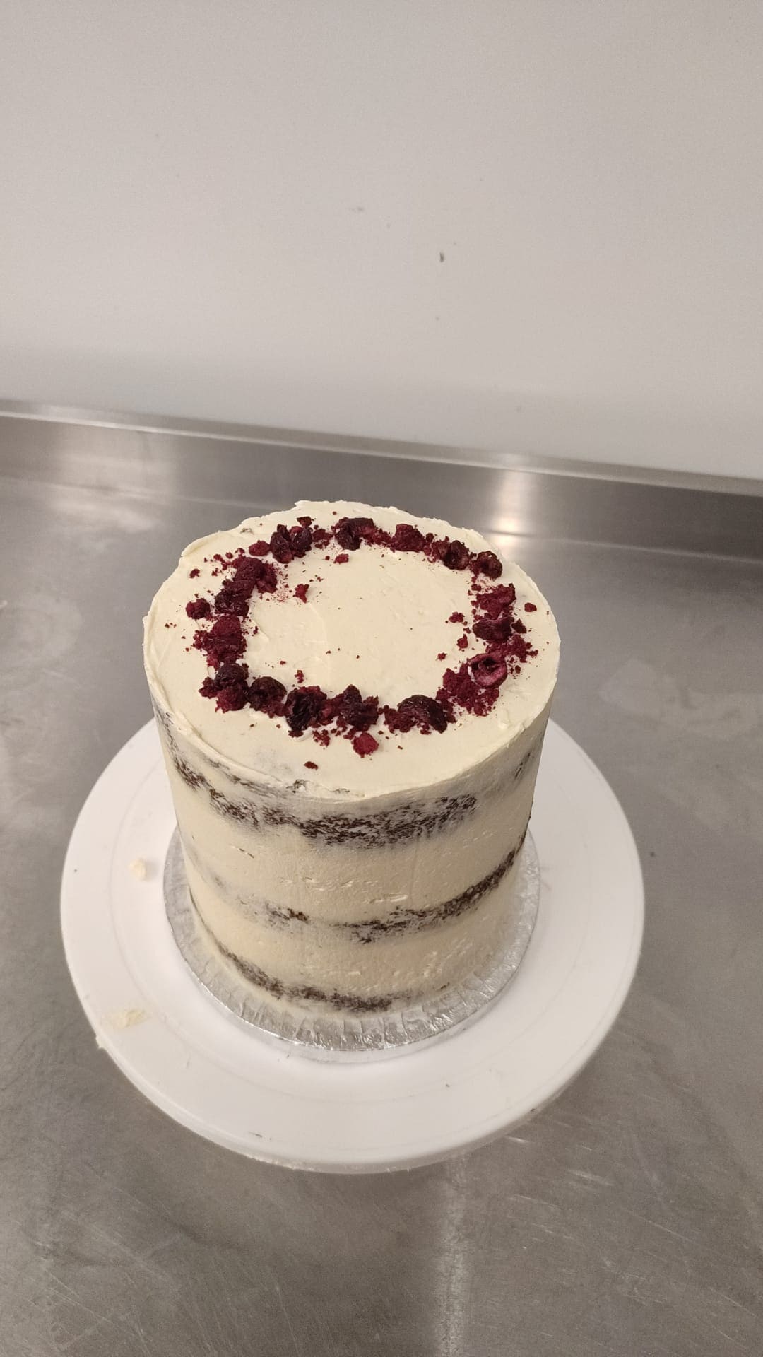 A No Guilt Bakes custom made low sugar cake sitting on a plate with raspberries on it, showcasing unique creations available for custom requests.