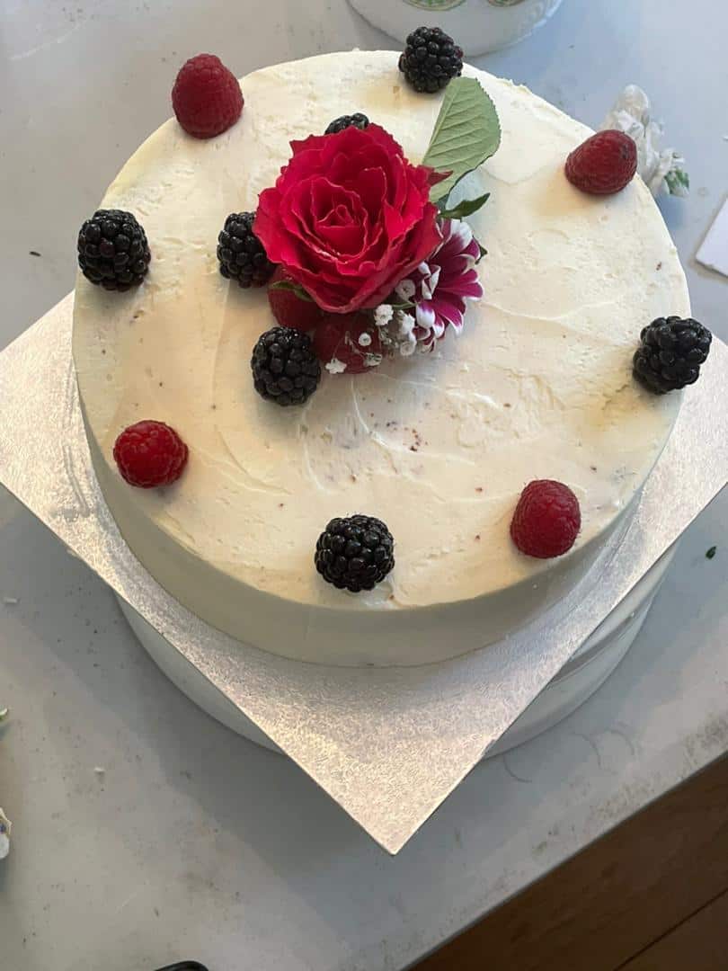 A Custom Made Low Sugar Cake adorned with juicy berries and a delicate rose, from No Guilt Bakes.