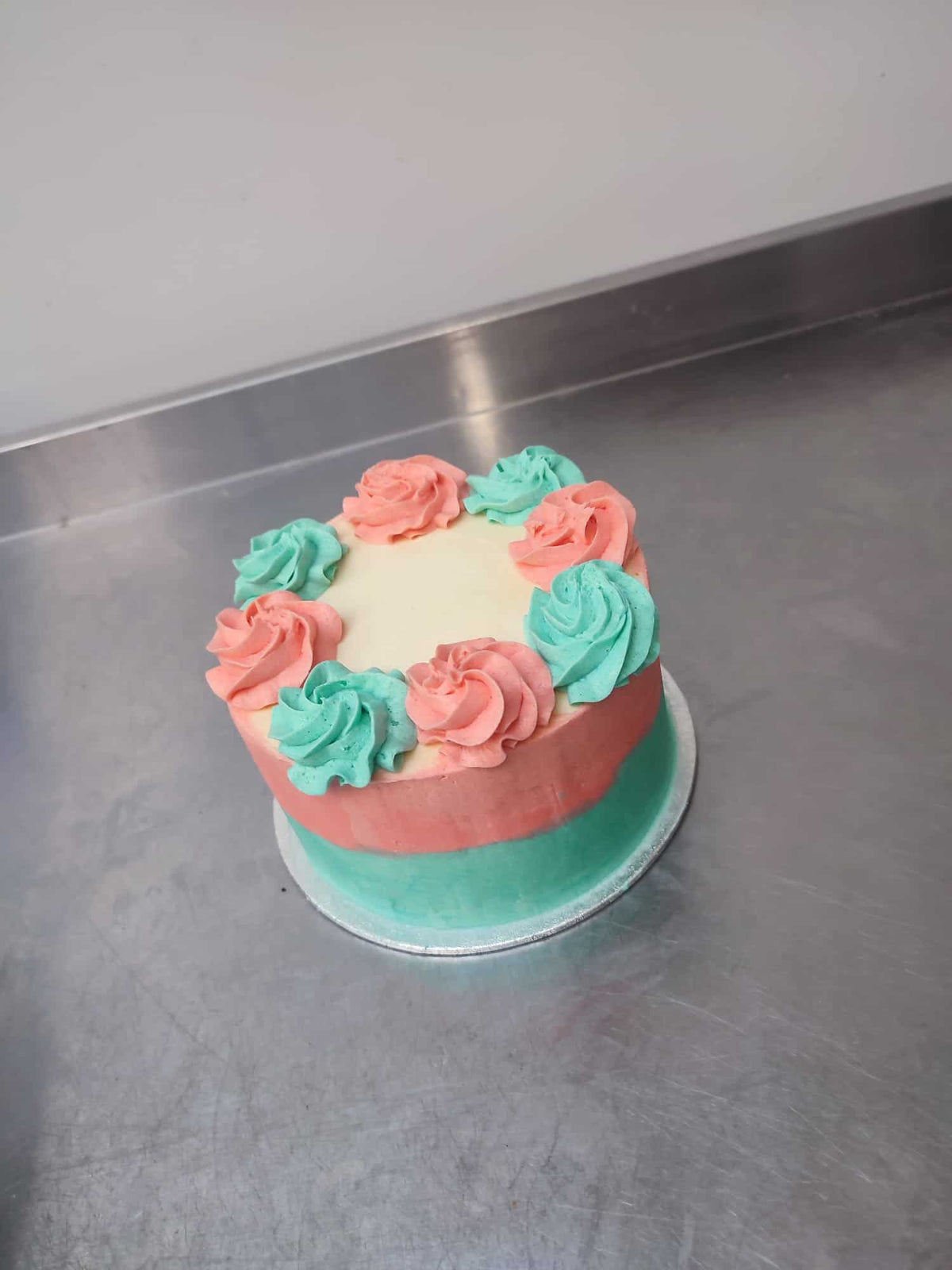 A Custom Made Low Sugar Cake adorned with pink, green, and blue flowers from No Guilt Bakes.