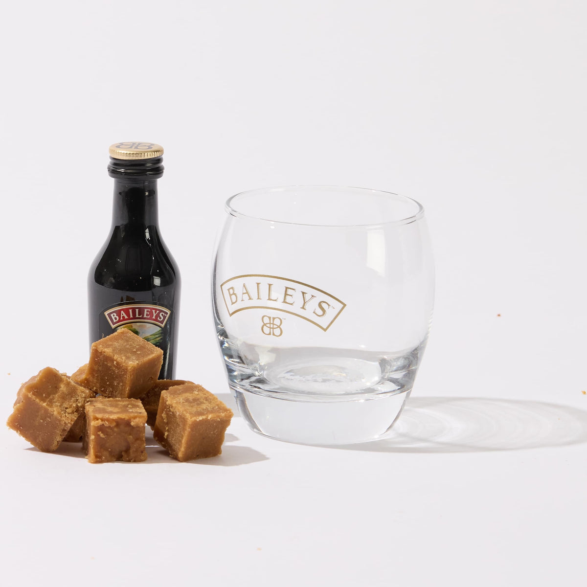 A guilt-free snack - a glass with a bottle of low-sugar No Guilt Bakes&#39; Irish Cream Flavour Keto Fudge and some caramels, perfect for those on a keto fudge diet.