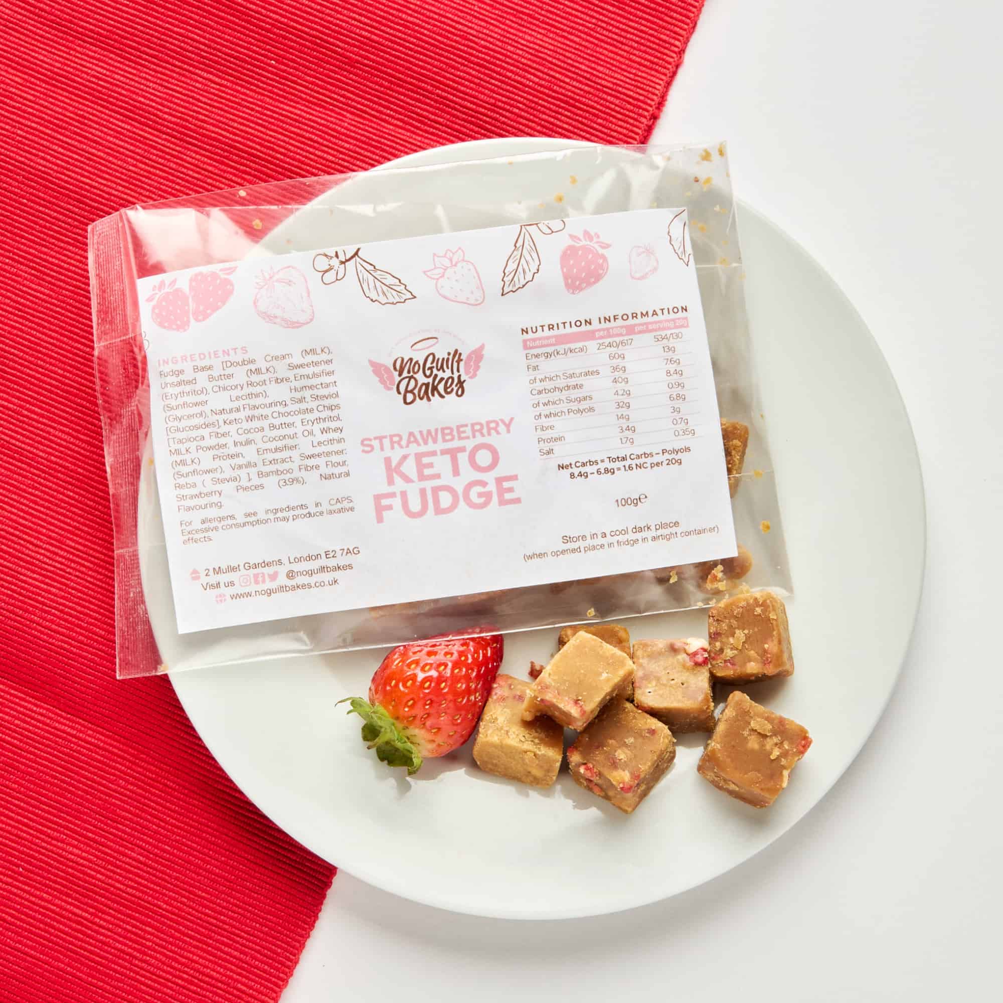 A plate with strawberries and a bag of No Guilt Bakes Strawberry Fudge, a delicious low-sugar treat.