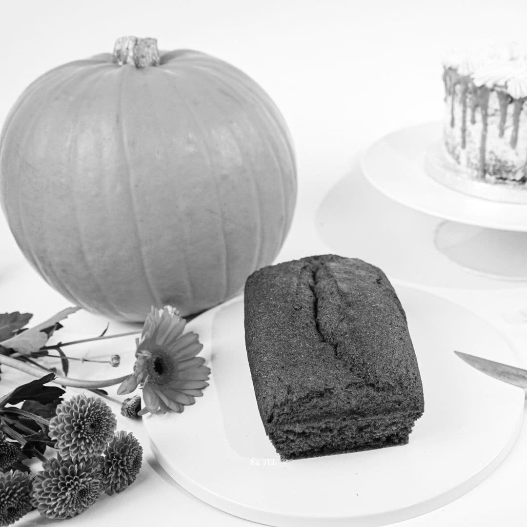 A black and white photo of a Pumpkin Keto Cake Loaf on a plate next to a No Guilt Bakes pumpkin loaf.